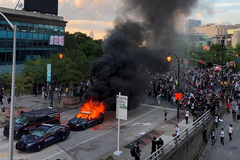 An Atlanta Police car burns as people protest against the death of George Floyd, near CNN Center in Atlanta, Georgia. REUTERS/Dustin Chambers  